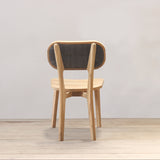 Outdoor wooden chair with rattan backrest on a wooden floor against a plain wall