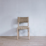 Woven chair against a plain white wall on a wooden floor.