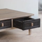 Wooden coffee table with black rattan drawers in a room setting