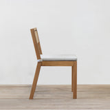 Wooden chair with grey cushion on a wooden floor and light gray wall