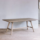 Reclaimed pine wood dining table in a minimalistic room with a light gray wall and wooden floor.