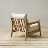 Wooden longue chair with white cushions on a wooden floor and light gray wall background