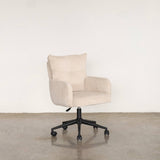 Beige upholstery chair with wheels on a stone floor against a grey wall.
