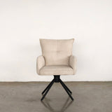 Beige upholstered dining chair on a stone floor against a plain wall