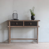 Reclaimed pine wood console table with decorative items against a light wall.