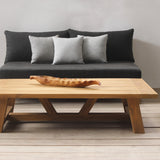 Modern outdoor furniture set with a wooden coffee table and gray sofa against a neutral wall.