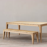 Outdoor dining table and bench set with slatted top on a wooden floor.