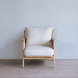 Wooden armchair with white cushion against a light blue wall.