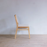Wooden chair against a plain white wall in a minimalistic room.