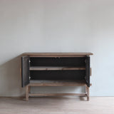 Reclaimed pine wood cabinet with open door in a minimalistic room with light-colored walls and wooden floor.
