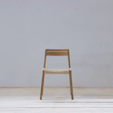 Wooden chair with woven seat on a light wooden floor and gray wall background