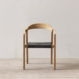 Outdoor rattan woven dining chair on a wooden floor against a plain wall