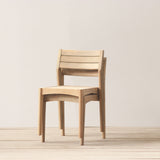 Stacked outdoor chairs on a light wooden floor with a plain white wall background