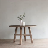 Reclaimed pine wood round dining table with a vase and candle.