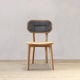 Outdoor wooden chair with rattan backrest on a wooden floor against a plain wall