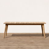 Wooden outdoor dining table with slatted top on a wooden floor with a white background