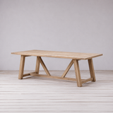 Wooden dining table on a light wooden floor and white wall background