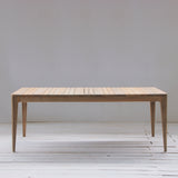 Outdoor dining table with slatted top on a wooden floor.