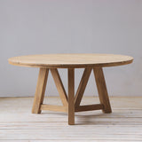 Wooden round dining table with slatted top on a wooden floor.