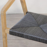 Outdoor rattan woven dining chair on a wooden floor against a plain wall