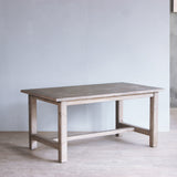 Reclaimed pine wood table in a minimalistic room with a gray wall and wooden floor.