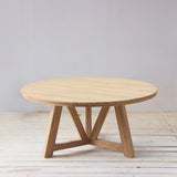 Wooden round dining table with slatted top on a wooden floor.