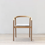 Outdoor dining chair with cushion on a wooden floor against a plain wall