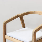 Outdoor dining chair with cushion on a wooden floor against a plain wall