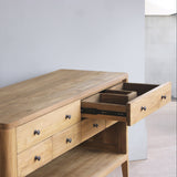 Wooden bathroom vanity with open drawer against a plain wall