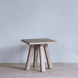 Reclaimed pine wood side table against a plain wall with a light gray color scheme