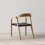 Outdoor rattan woven dining chair on a wooden floor against a plain wall
