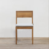 Wooden chair with a grey cushion on a wooden floor and white wall background