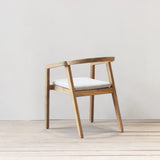 Outdoor dining chair with cushion on a wooden floor against a plain wall