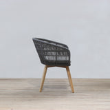 Rattan chair with wooden legs on a wooden floor against a light gray wall