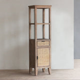 Tall wooden cabinet with rattan door and drawer against a plain wall.
