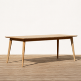 Wooden outdoor dining table with slatted top on a wooden floor with a white background