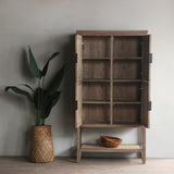 Wooden cabinet with open doors, a plant, and a bowl on a neutral background