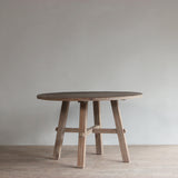 Reclaimed pine wood round dining table in a minimalistic room with a neutral color scheme.