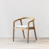 Outdoor dining chair with cushion on a wooden floor against a plain wall