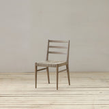 Reclaimed pine wood chair with pandan seat on a wooden floor against a plain wall