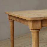 Wooden outdoor dining table on a wooden floor against a plain wall.
