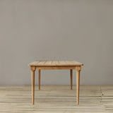 Wooden outdoor dining table on a wooden floor against a plain wall.