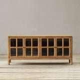 Wooden sideboard with glass doors on a wooden floor against a plain wall