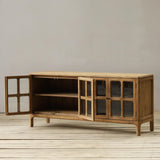 Wooden sideboard with open doors on a wooden floor against a plain wall