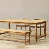 Wooden dining table and bench set on a wooden floor with a neutral background