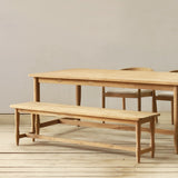 Wooden dining table and bench set on a wooden floor with a neutral background