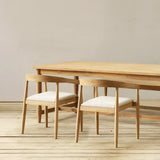 Wooden dining table with chairs on a wooden floor against a plain wall