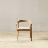 Wooden chair with a white cushion on a wooden floor and light gray wall