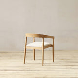 Wooden chair with a white cushion on a wooden floor and light gray wall