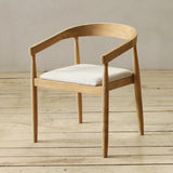 Wooden chair with a white cushion on a wooden floor.